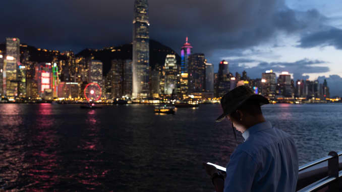 A person checks a smartphone along the Victoria Harbour waterfront in Tsim Sha Tsui in Hong Kong, China, on Tuesday, July 7, 2020.