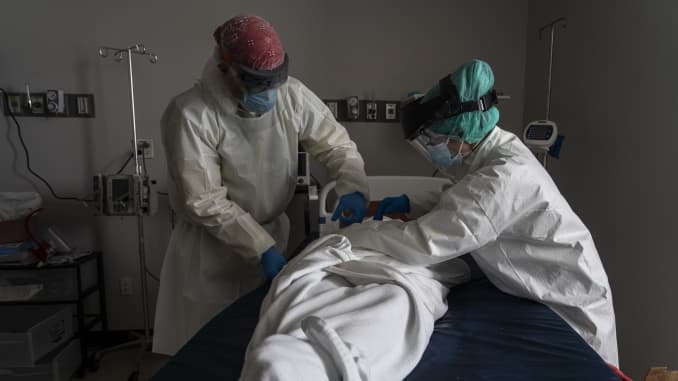Medical staffers wear full PPE as they wrap a deceased patient with bed sheets in the Covid-19 intensive care unit at the United Memorial Medical Center on June 30, 2020 in Houston, Texas.