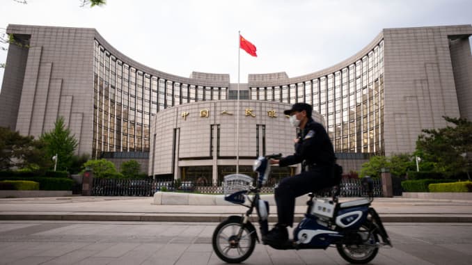 A man wears a protective mask as he rides past the The People's Bank of China in Beijing.