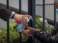 Una persona que usa una máscara protectora recibe desinfectante para manos mientras asistía a misa fuera del Santuario Nacional de la Iglesia Católica de San Francisco de Asís en San Francisco, California, el martes 14 de julio de 2020.