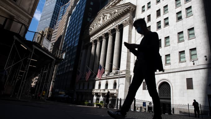 Un peatón con una máscara facial mira un teléfono inteligente mientras pasa frente a la Bolsa de Valores de Nueva York (NYSE) en Nueva York, el lunes 20 de julio de 2020.