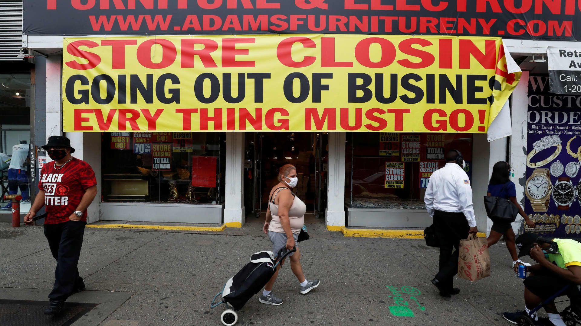 People walk by a store going out of business along 125th street in the Harlem neighborhood of New York City, August 7, 2020.