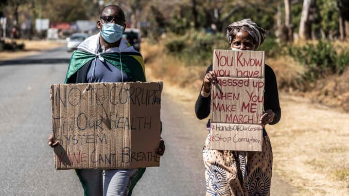 HARARE, Zimbabwe - A man and a woman hold placards during an anti-corruption protest march along Borrowdale road, on July 31, 2020 in Harare. Police in Zimbabwe arrested on July 31, 2020 internationally-aclaimed novelist Tsitsi Dangarembga as they enforced a ban on protests coinciding with the anniversary of President Emmerson Mnangagwa's election.
