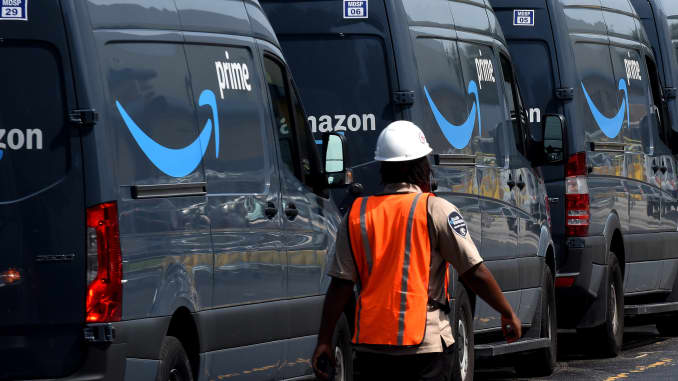 Amazon vans line up at a distribution center to pick up packages for delivery on Amazon Prime Day, July 16, 2019, in Orlando, Florida.