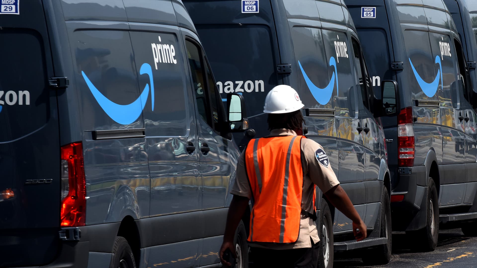 Amazon vans line up at a distribution center to pick up packages for delivery on Amazon Prime Day in Orlando, Florida.