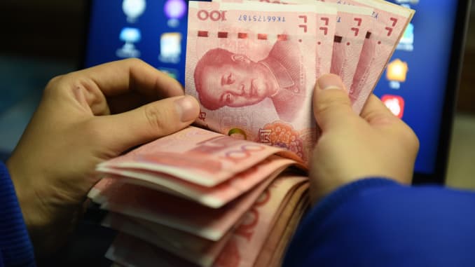 Un hombre que cuenta 100 billetes de renminbi, la moneda china.