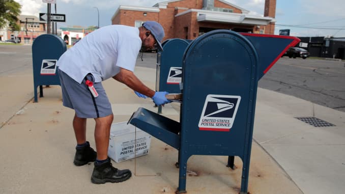 A United States Postal Service (USPS) worker handles the mail in a drop-off box behind a post office in Oak Park, Michigan, August 17, 2020.