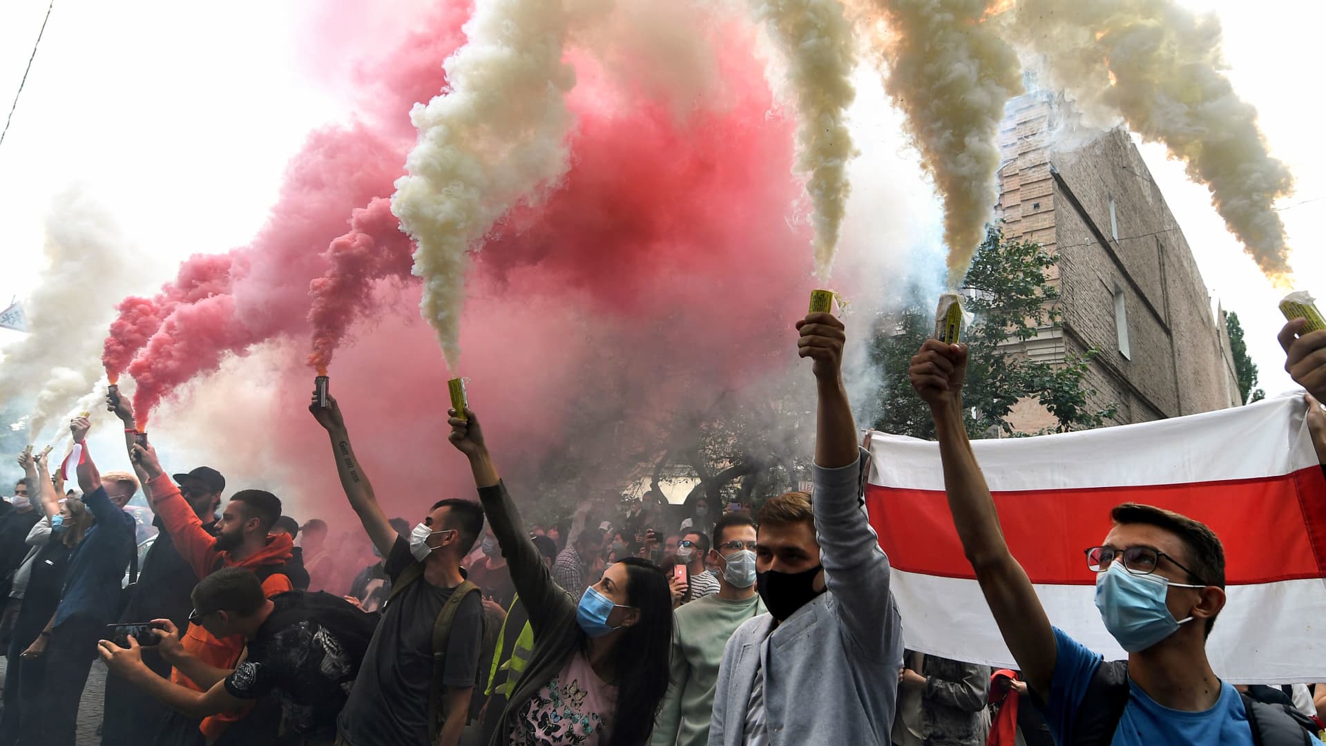 Members of the Belarus diaspora and Ukrainian activists burn white and red smoke grenades during a rally in support of Belarus people protesting vote rigging in the presidential election, outside the Belarusian embassy in Kiev on August 13, 2020.