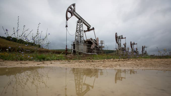Oil pumping jacks, also known as "nodding donkeys", are reflected in a puddle as they operate in an oilfield near Almetyevsk, Russia, on Sunday, Aug. 16, 2020.