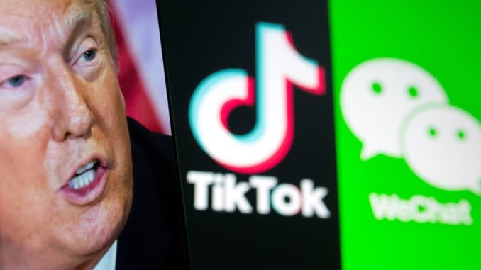 A picture of U.S. President Donald Trump is seen on a smartphone in front of displayed Tik Tok and WeChat logos in this illustration taken September 18, 2020.