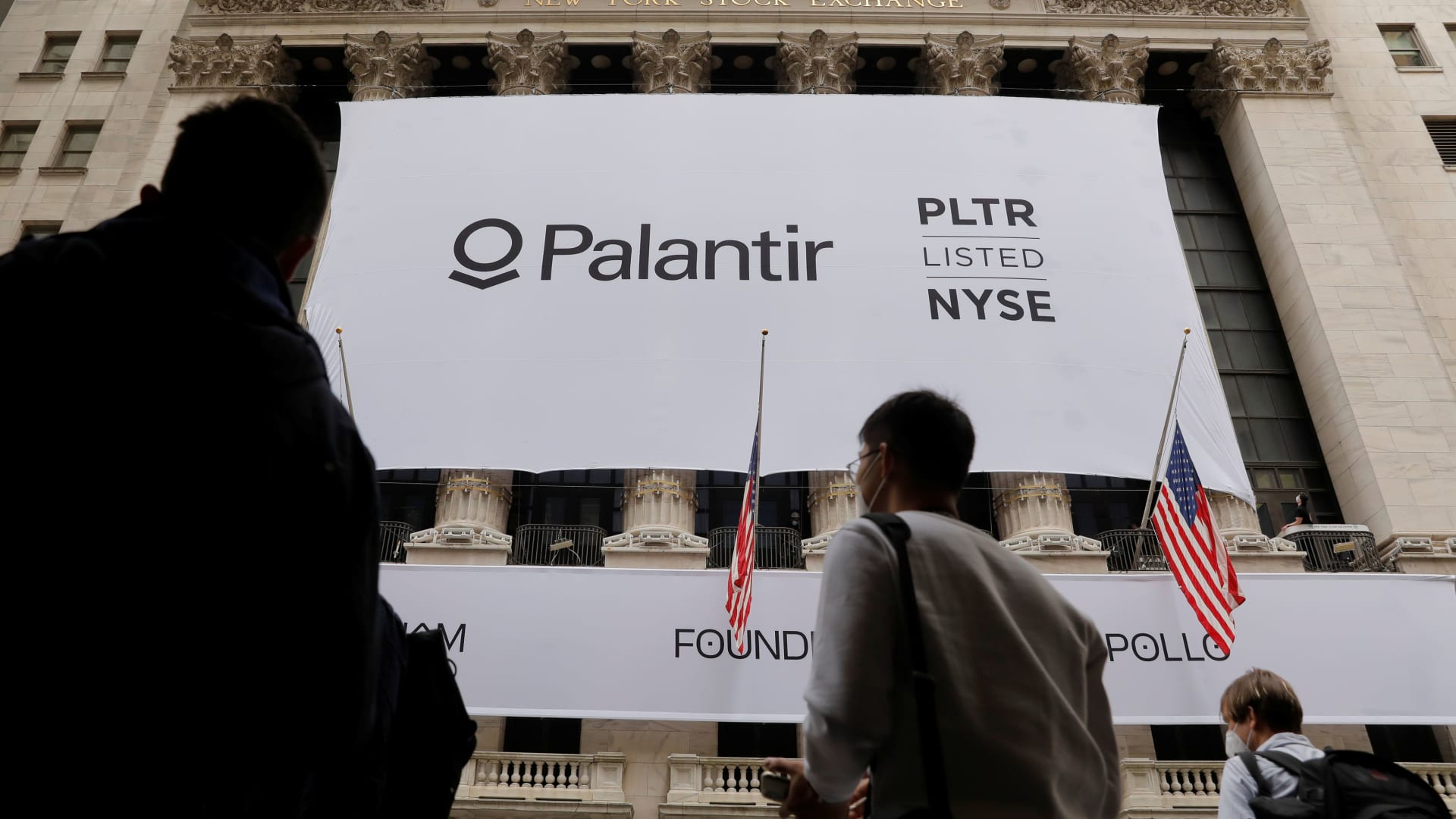 People walk by a banner featuring the logo of Palantir Technologies (PLTR) at the New York Stock Exchange (NYSE) on the day of their initial public offering (IPO) in Manhattan, New York City, U.S., September 30, 2020.