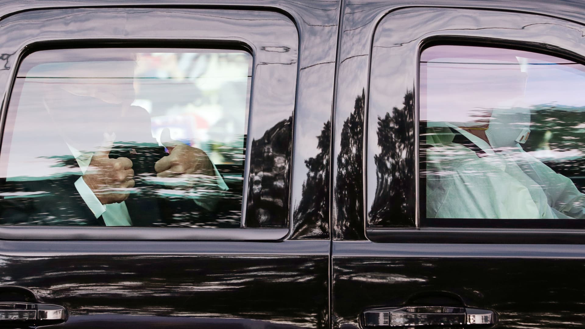 U.S. President Donald Trump gives two thumbs up to supporters as he rides in the presidential SUV with two U.S. Secret Service agents wearing medical protective masks, goggles and protective gowns in the front seat as they drive past the front of Walter Reed National Military Medical Center, where he is being treated for coronavirus disease (COVID-19) in Bethesda, Maryland, U.S. October 4, 2020.
