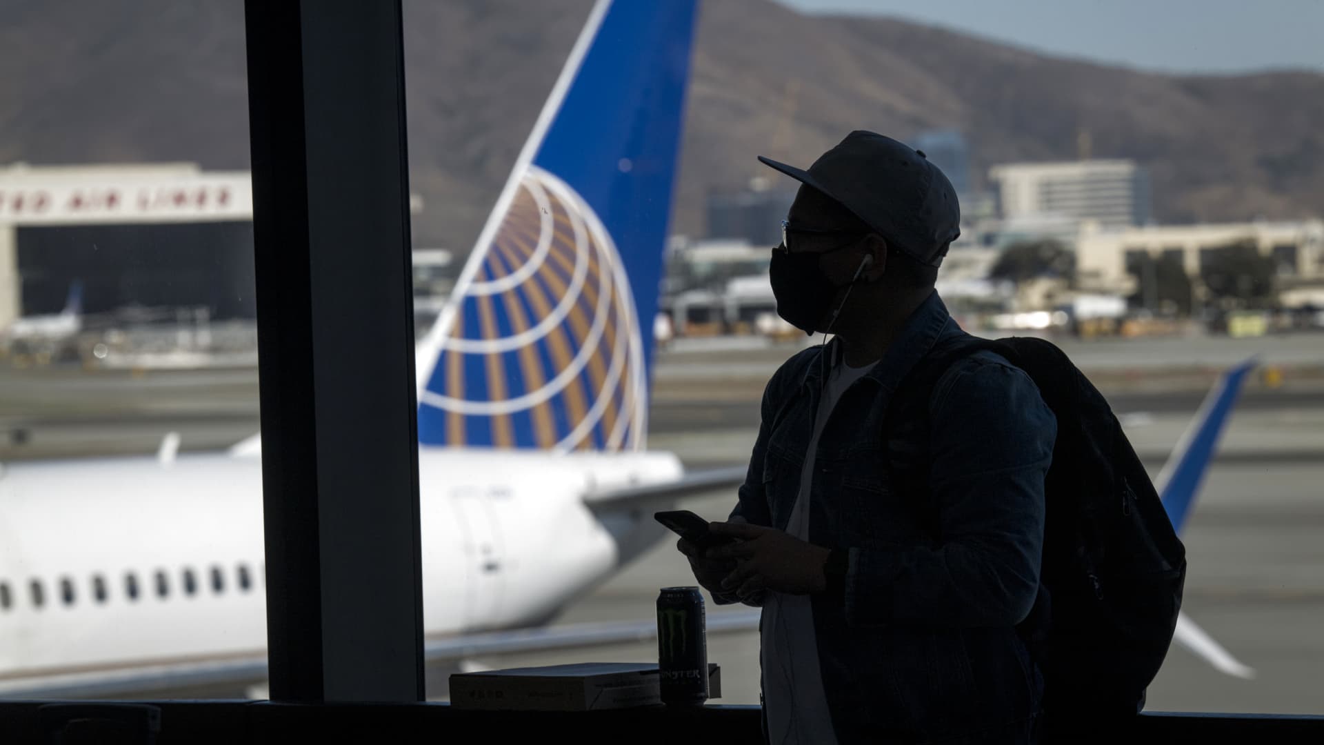 A traveler wearing a protective mask waits to board a United Airlines flight at San Francisco International Airport, Oct. 15, 2020.