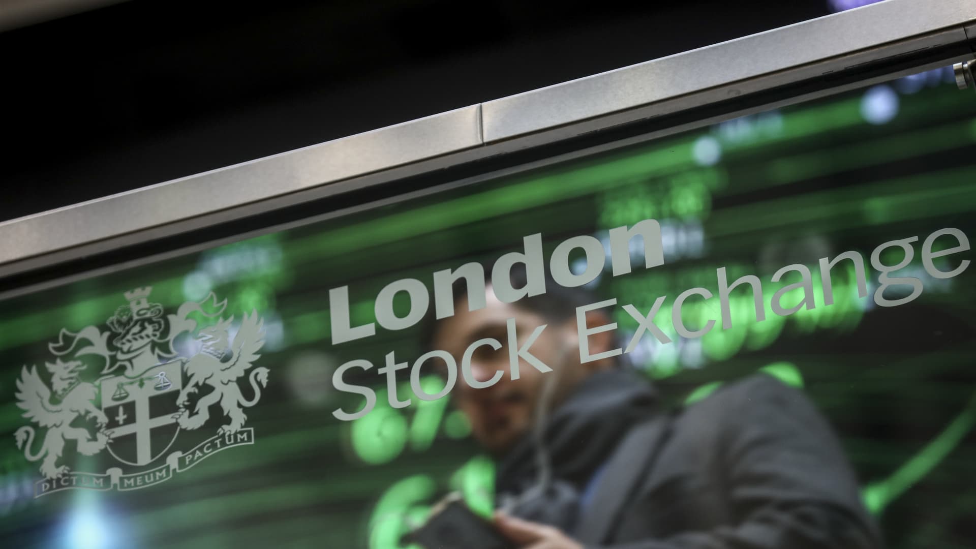 An employee sits reflected in a glass screen featuring the London Stock Exchange Group Plc's logo at their offices in London, U.K., on Thursday, Jan. 2, 2020.