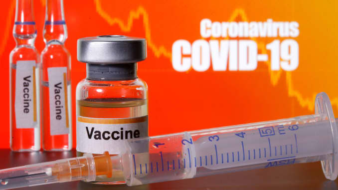 Các chai nhỏ có nhãn dán "Vắc xin" đặt gần ống tiêm y tế phía trước dòng chữ "Coronavirus COVID-19" được hiển thị trong hình minh họa này được chụp vào ngày 10 tháng 4 năm 2020.