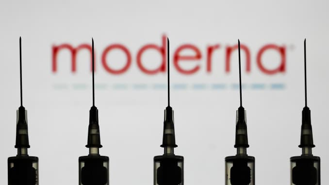 Medical syringes are seen with Moderna company logo displayed on a screen in the background in this illustration photo taken in Poland on October 12, 2020.