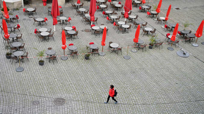 Bavaria, Munich: A pedestrian walks past an empty street cafe in the pedestrian zone.