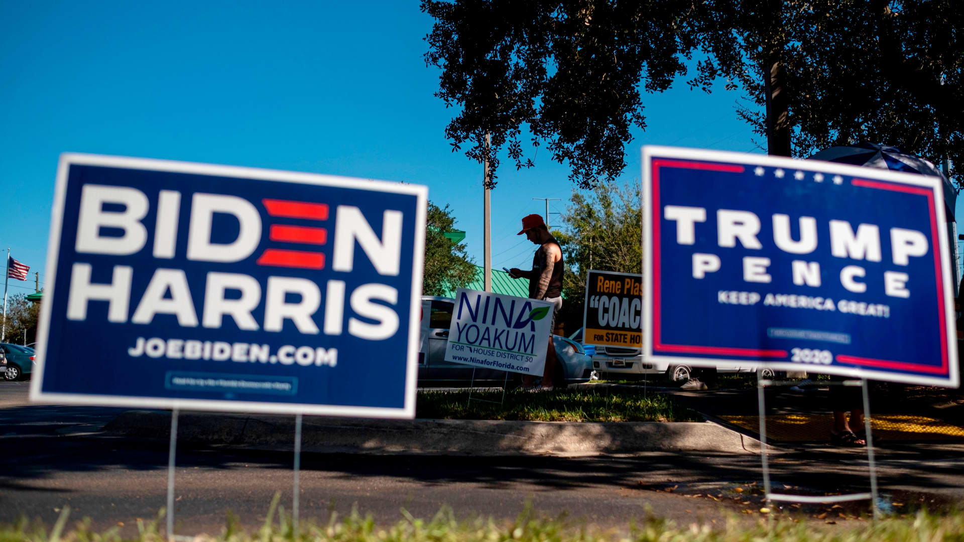 Biden and Trump campaign signs are displayed as voters line up to cast their ballots during early voting at the Alafaya Branch Library in Orlando, Florida, Oct. 30, 2020.