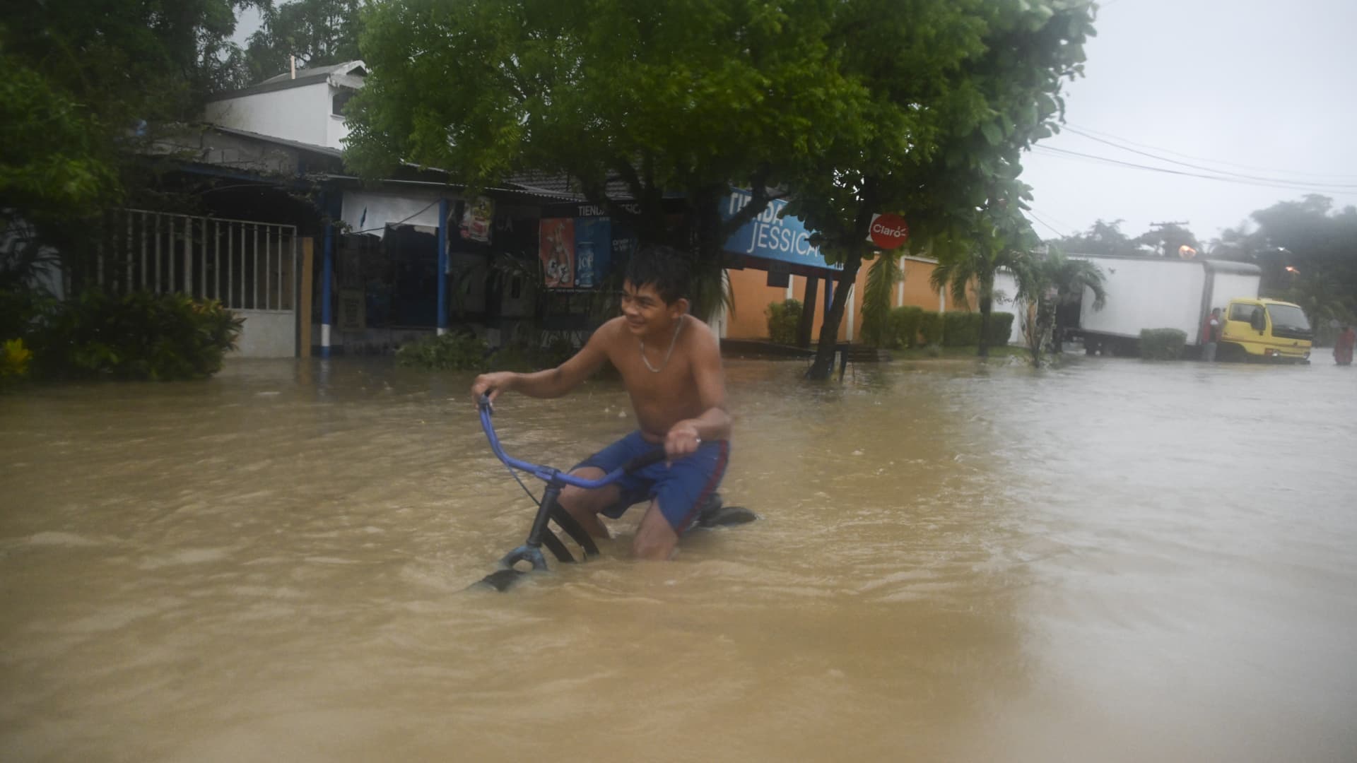 A boy rides a bicycle along a flooded street due to the heavy rains caused by Hurricane Eta, now degraded to a tropical storm, in Puerto Barrios, Izabal 310 km north Guatemala City on November 5, 2020.