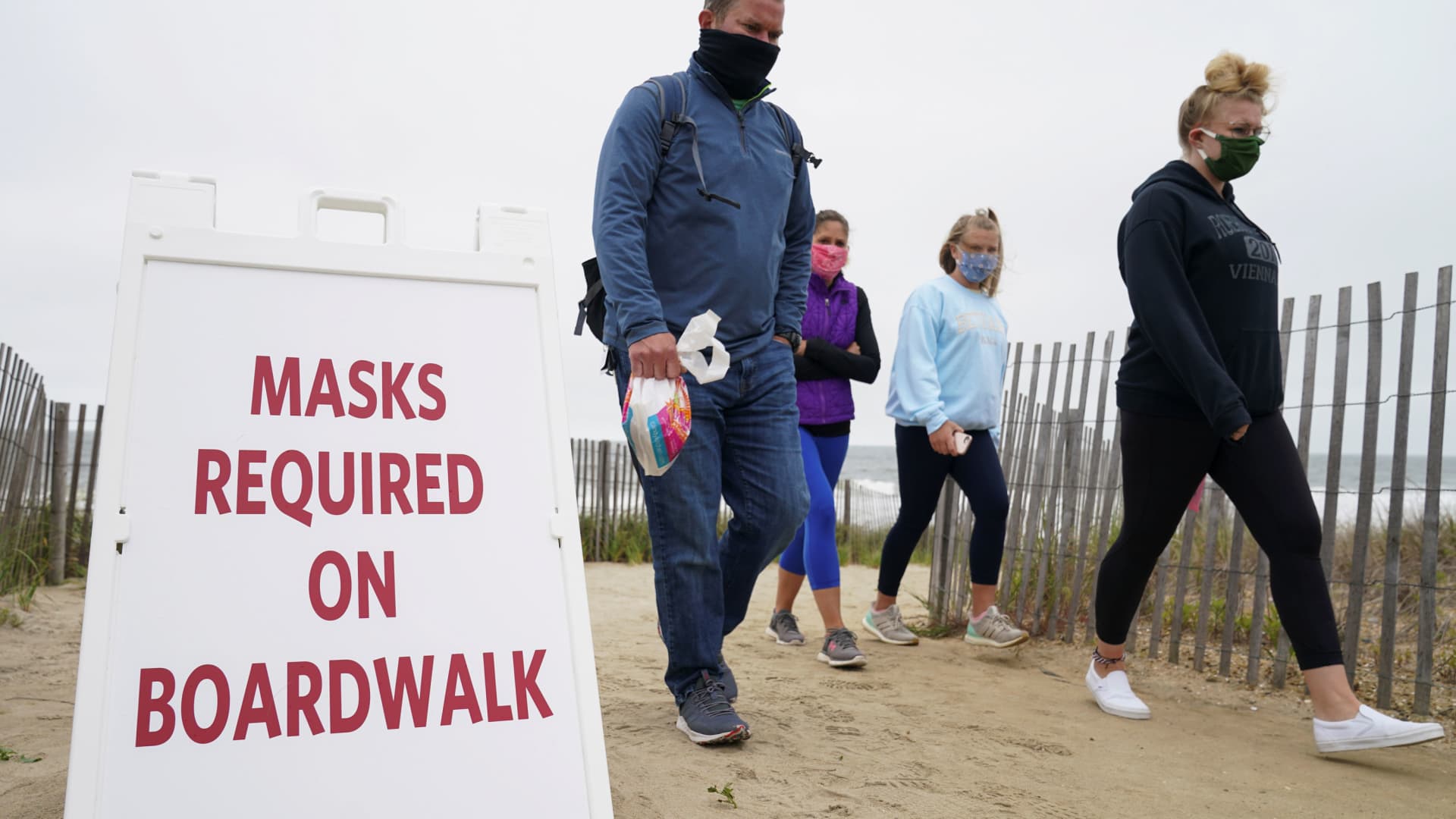 Visitors walk past a sign requiring face masks to stop the spread of the coronavirus disease (COVID-19) during Memorial Day weekend at Bethany Beach, Delaware, May 24, 2020.