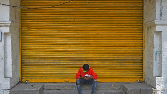 Un hombre se sienta frente a una tienda minorista cerrada en una calle durante un cierre para contener el aumento de casos de coronavirus Covid-19, en Bangalore el 20 de julio de 2020.