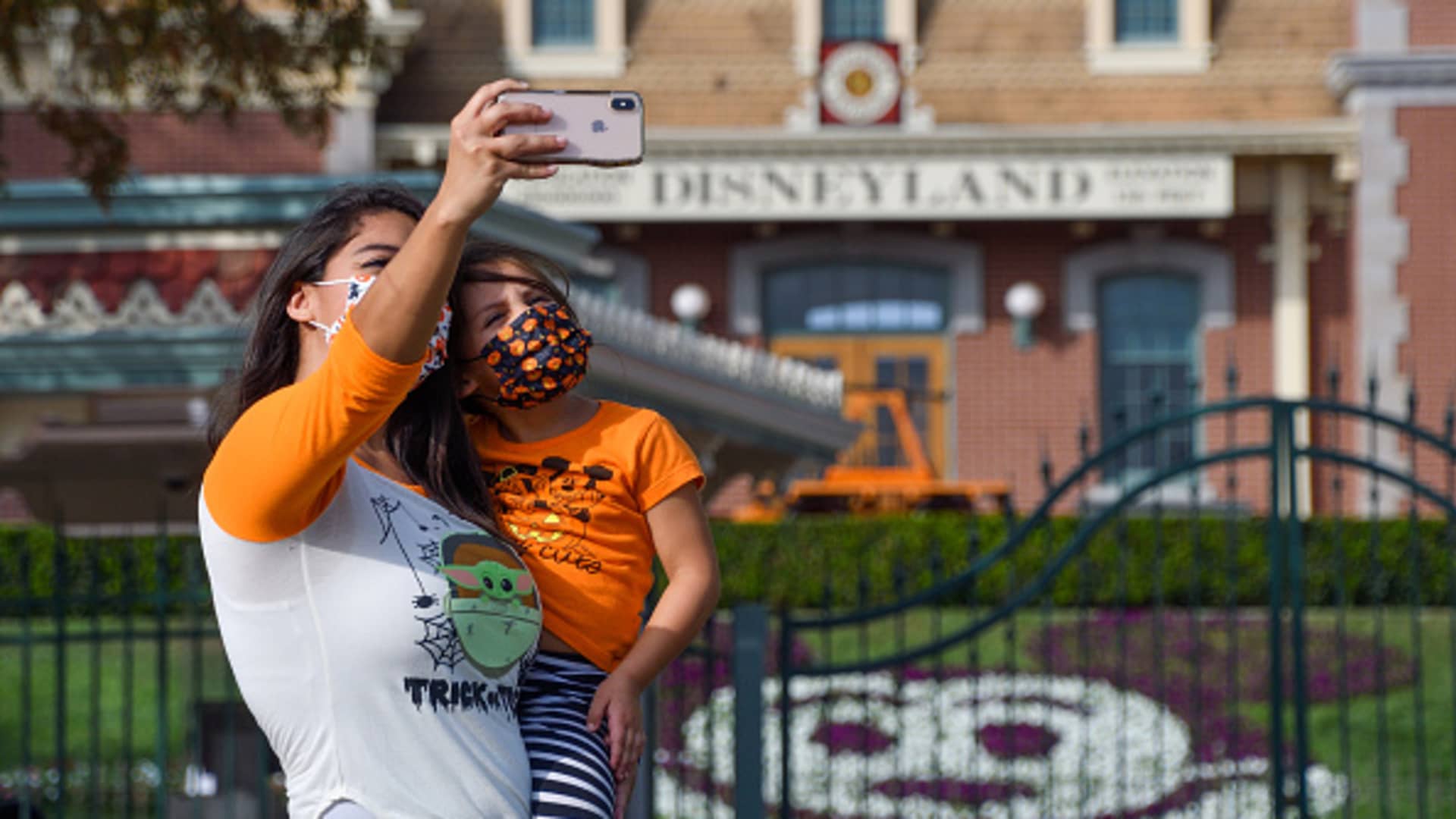 Brittany Losey takes a picture with her daughter Madison Losey, 7, outside the entrance to Disneyland at the Disneyland Resort is closed in Anaheim, CA, on Thursday, October 22, 2020.