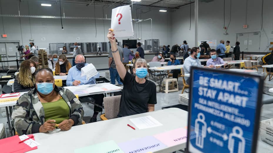 A Gwinnett county worker raises a piece of paper saying that they have a question as they begin their recount of the ballots on November 13, 2020 in Lawrenceville, Georgia.