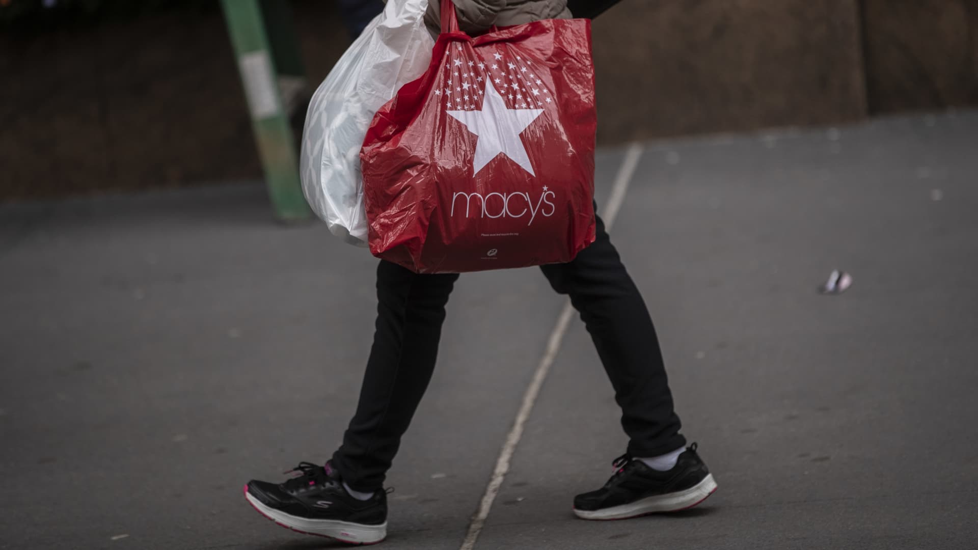 A pedestrian carries a Macy's Inc. branded shopping bag outside the company's flagship store in the Herald Square area of New York, U.S., on Tuesday, Nov. 17, 2020.