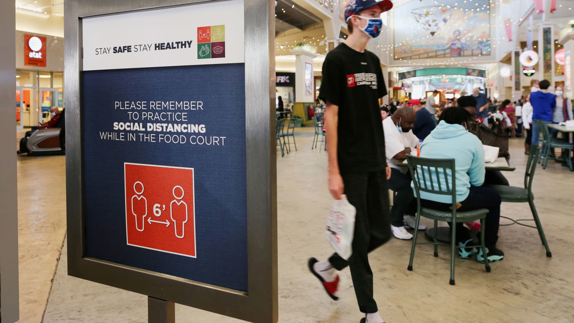 A shopper wearing a protective mask passes a social distancing sign at Coastal Grand Mall on Black Friday, in Myrtle Beach, South Carolina, November 27, 2020.