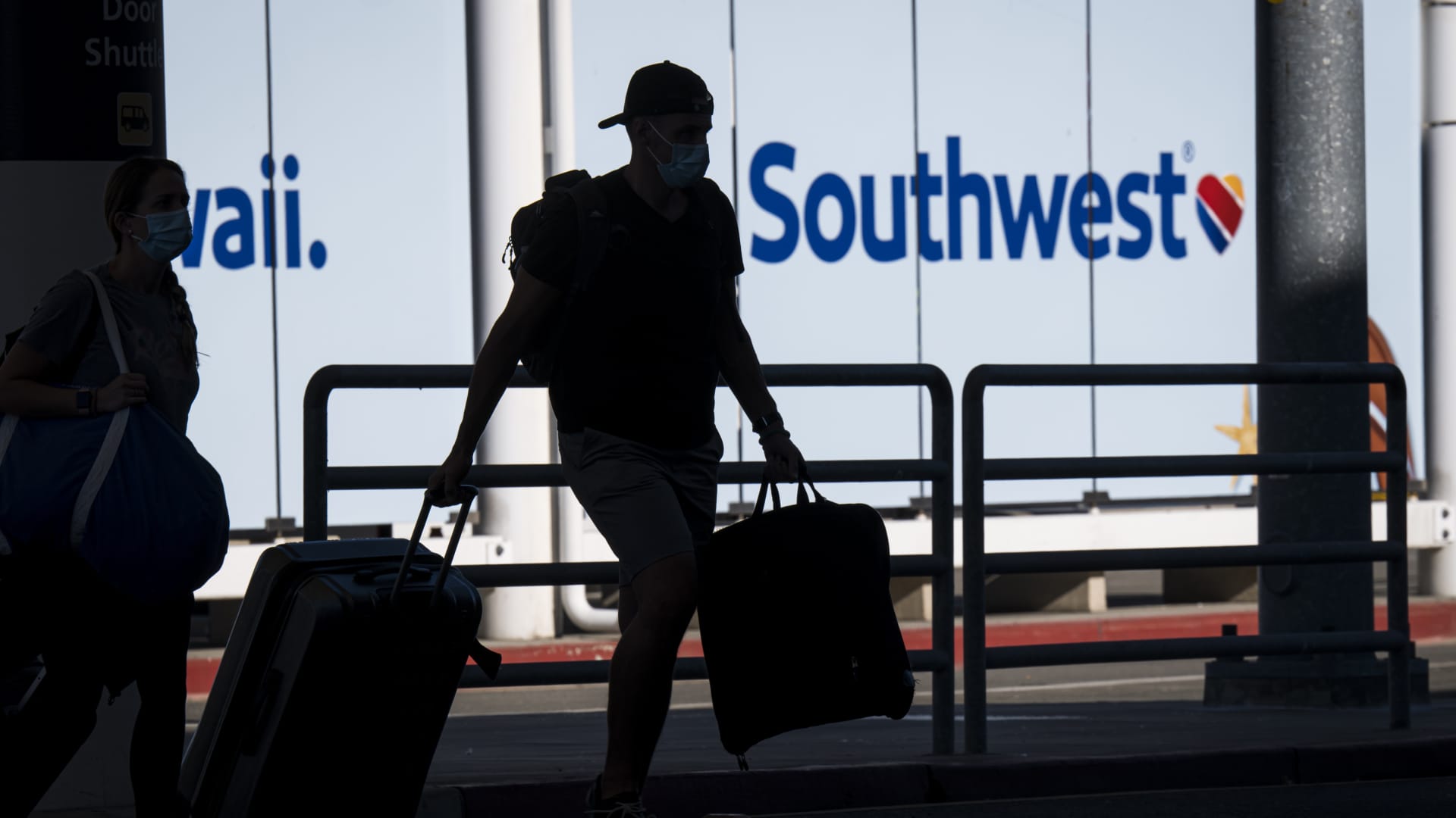 Travelers wearing protective masks cross a street outside a Southwest Airlines Co. check-in area at Oakland International Airport in Oakland, California, U.S., on Monday, Oct. 19, 2020.