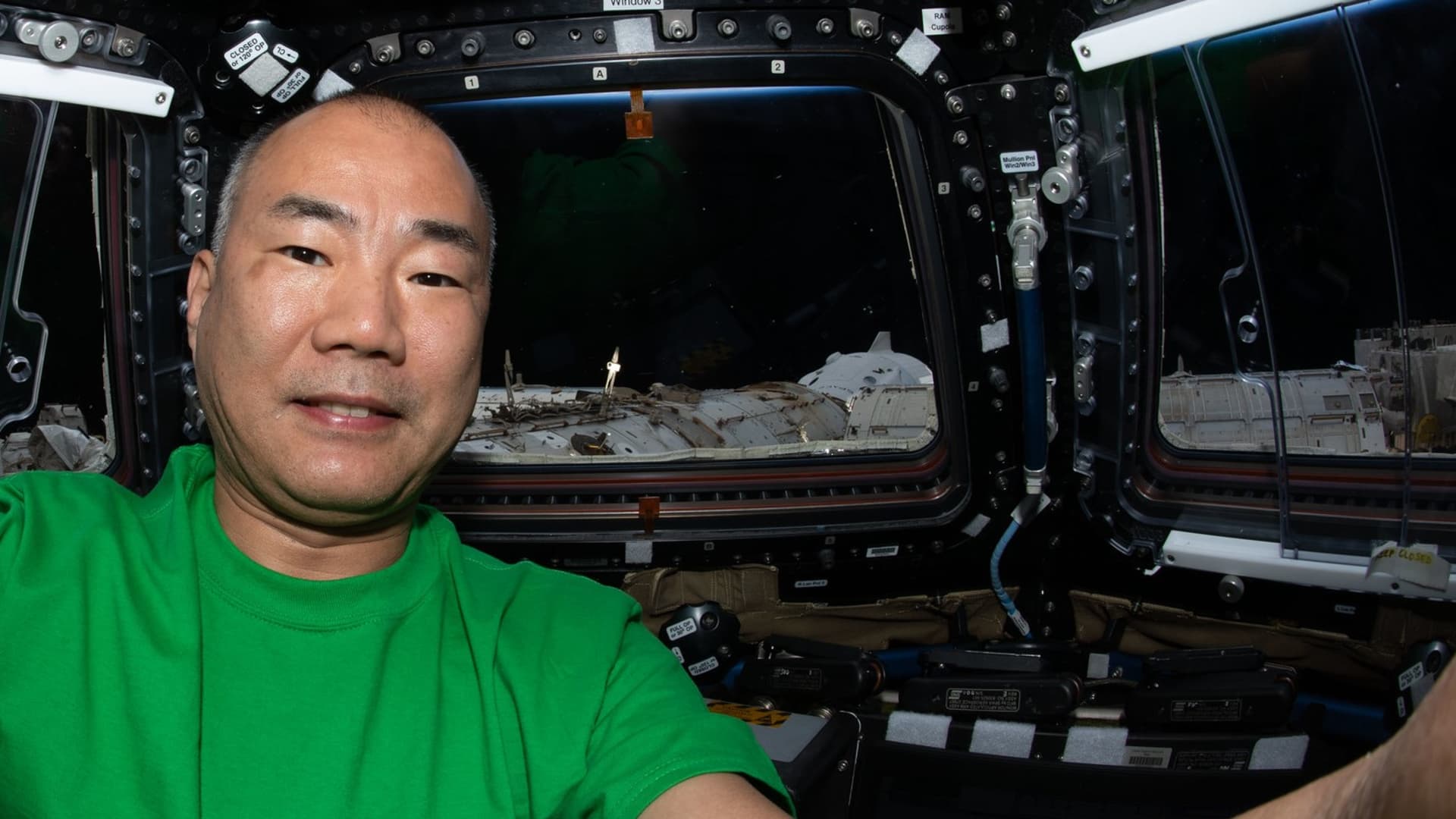 Japanese astronaut Soichi Noguchi poses in the International Space Station, with SpaceX's Crew Dragon capsule Resilience seen docked in the background.
