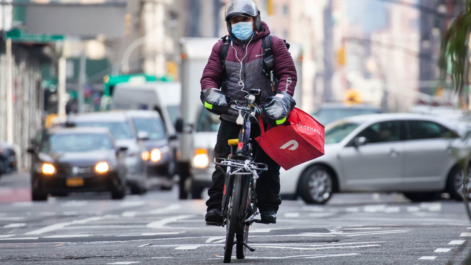 A bike messenger carries a DoorDash bag during a delivery in New York, Wednesday, Dec. 9, 2020.