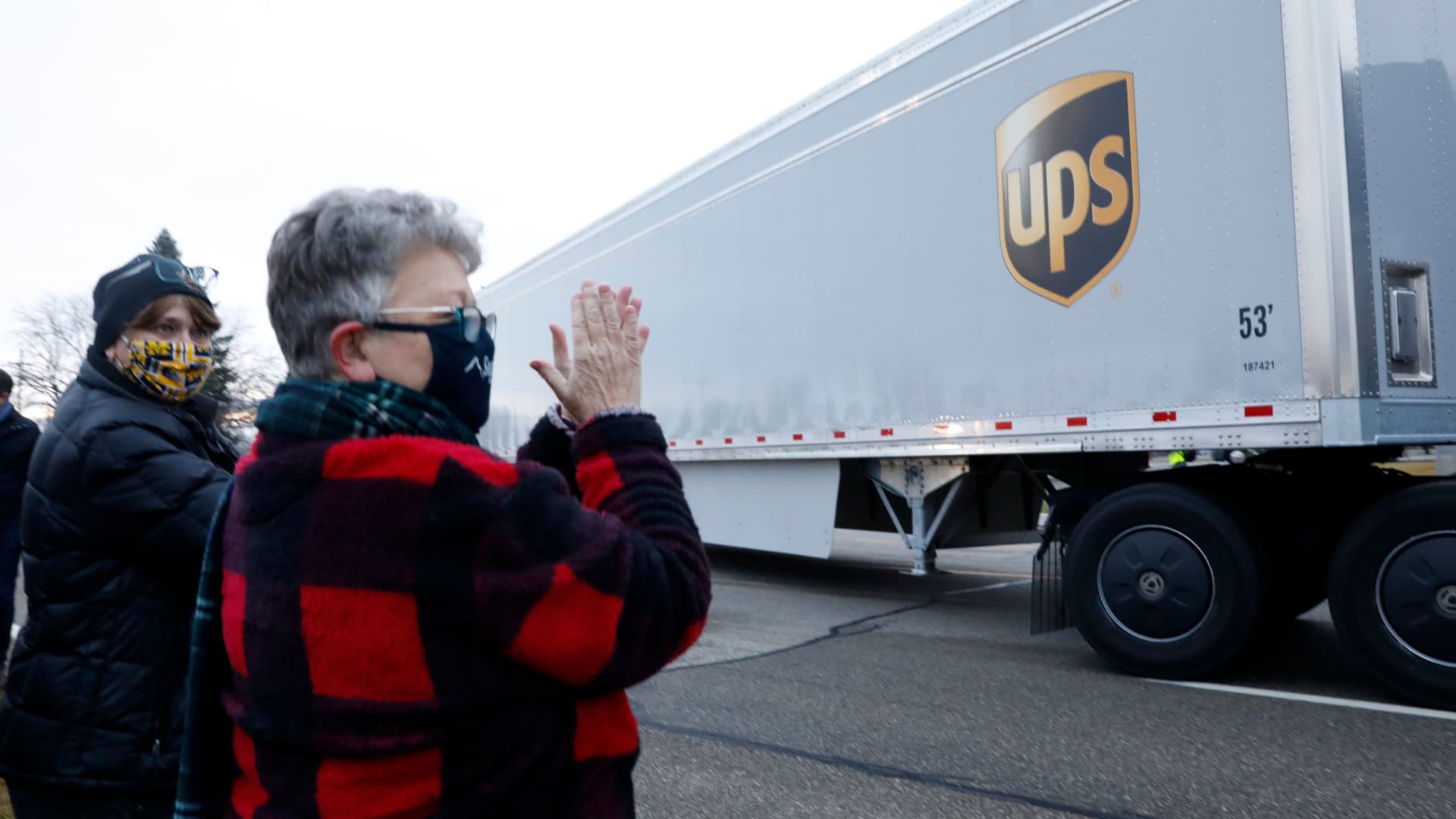 Nancy Galloway (L) and Susan Deur cheer as trucks carrying the first shipment of the Covid-19 vaccine that is being escorted by the US Marshals Service, leave Pfizer's Global Supply facility in Kalamazoo, Michigan on December 13, 2020.