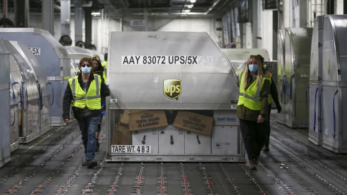 UPS employees move one of two shipping containers containing the first shipments of the Pfizer and BioNTech COVID-19 vaccine inside a sorting facility at UPS Worldport on December 13, 2020 in Louisville, Kentucky.