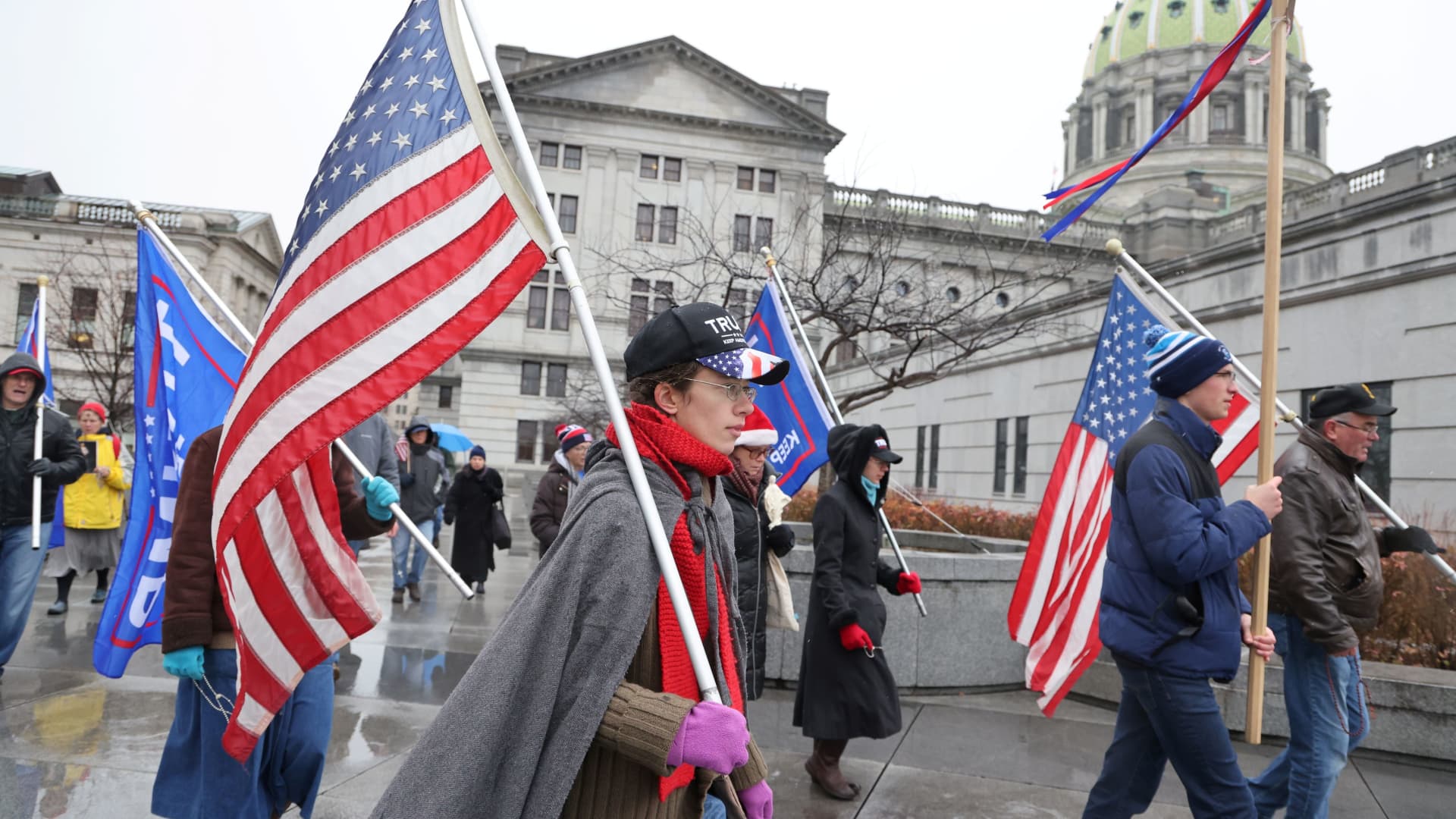 A small band of Trump supporters march with flags as electors gathered to cast their votes for the U.S. presidential election at the State Capitol complex in Harrisburg, Pennsylvania, U.S. December 14, 2020.