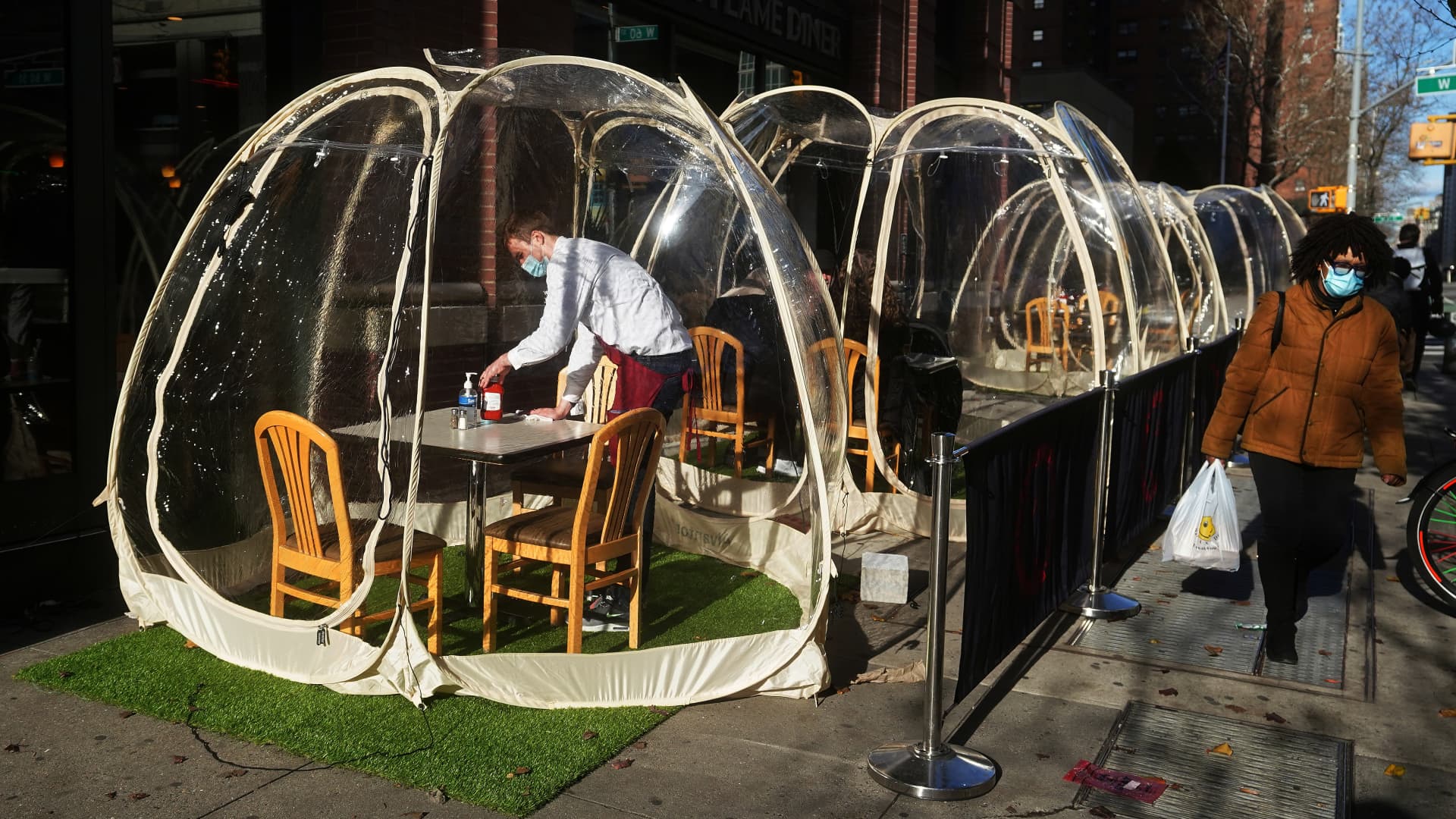 A New York waiter sets a table in a plastic bubble outside the Olympic Flame Diner in Manhattan on Dec. 15, 2020.