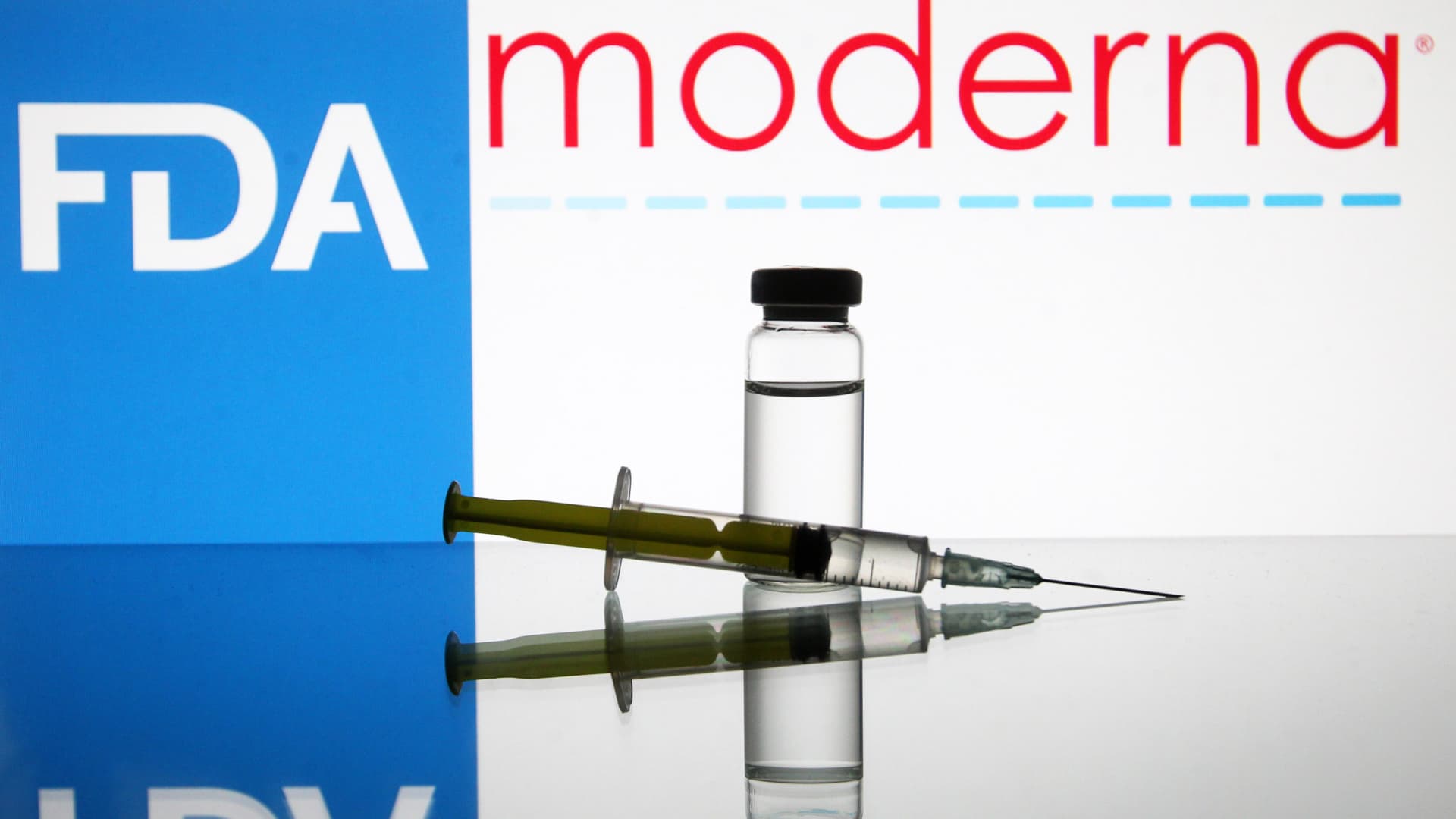 A vial and a medical syringe seen displayed in front of the Food and Drug Administration (FDA) of the United States and Moderna biotechnology company's logos. FDA finds the COVID-19 vaccine.