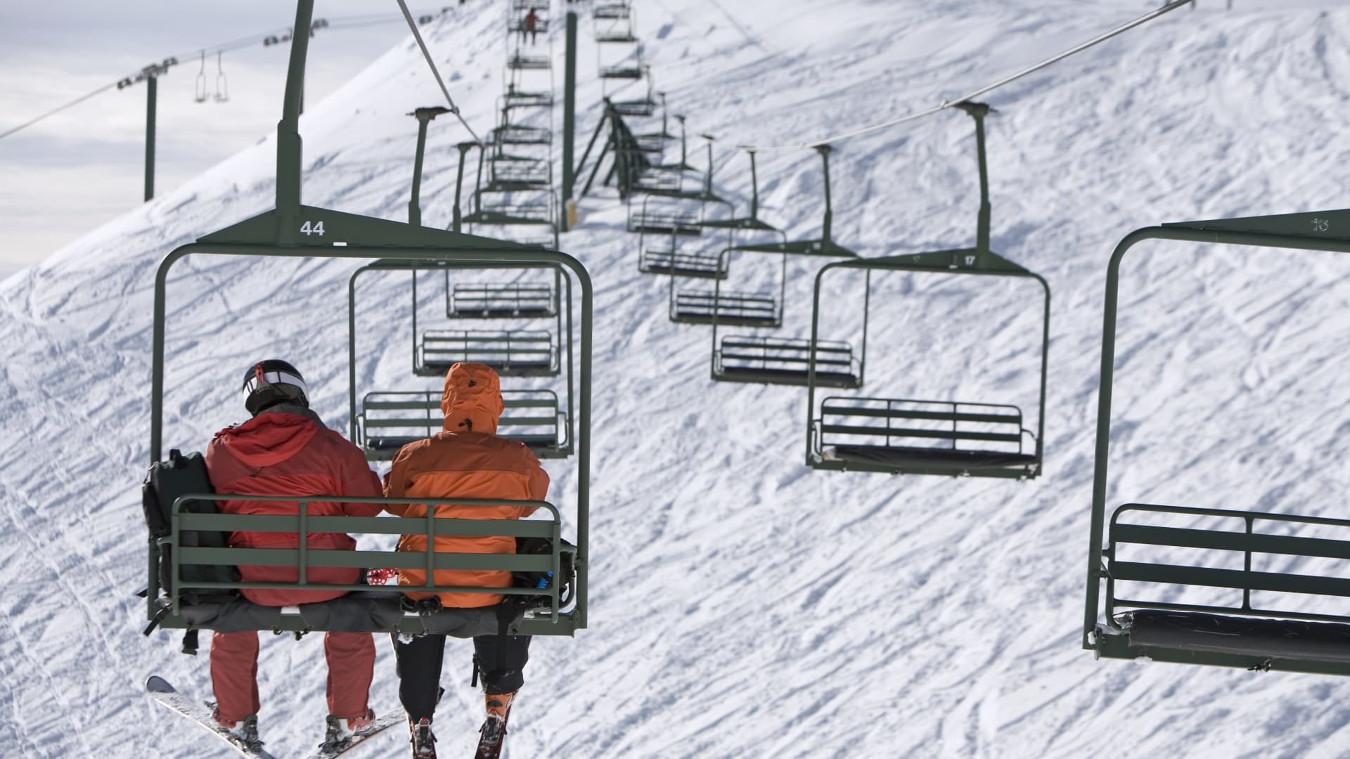 Skiers ascend the slopes on a socially distanced ski lift.