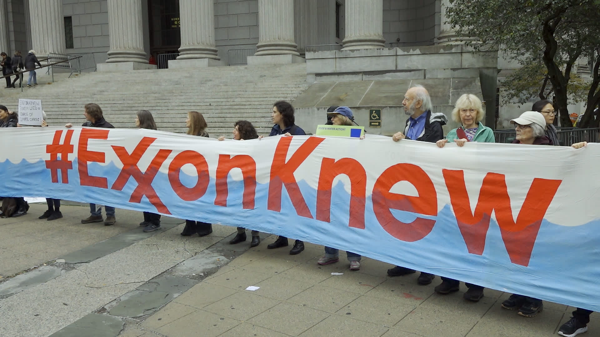 People protest against ExxonMobil before the start of its trial outside the New York State Supreme Court building on October 22, 2019