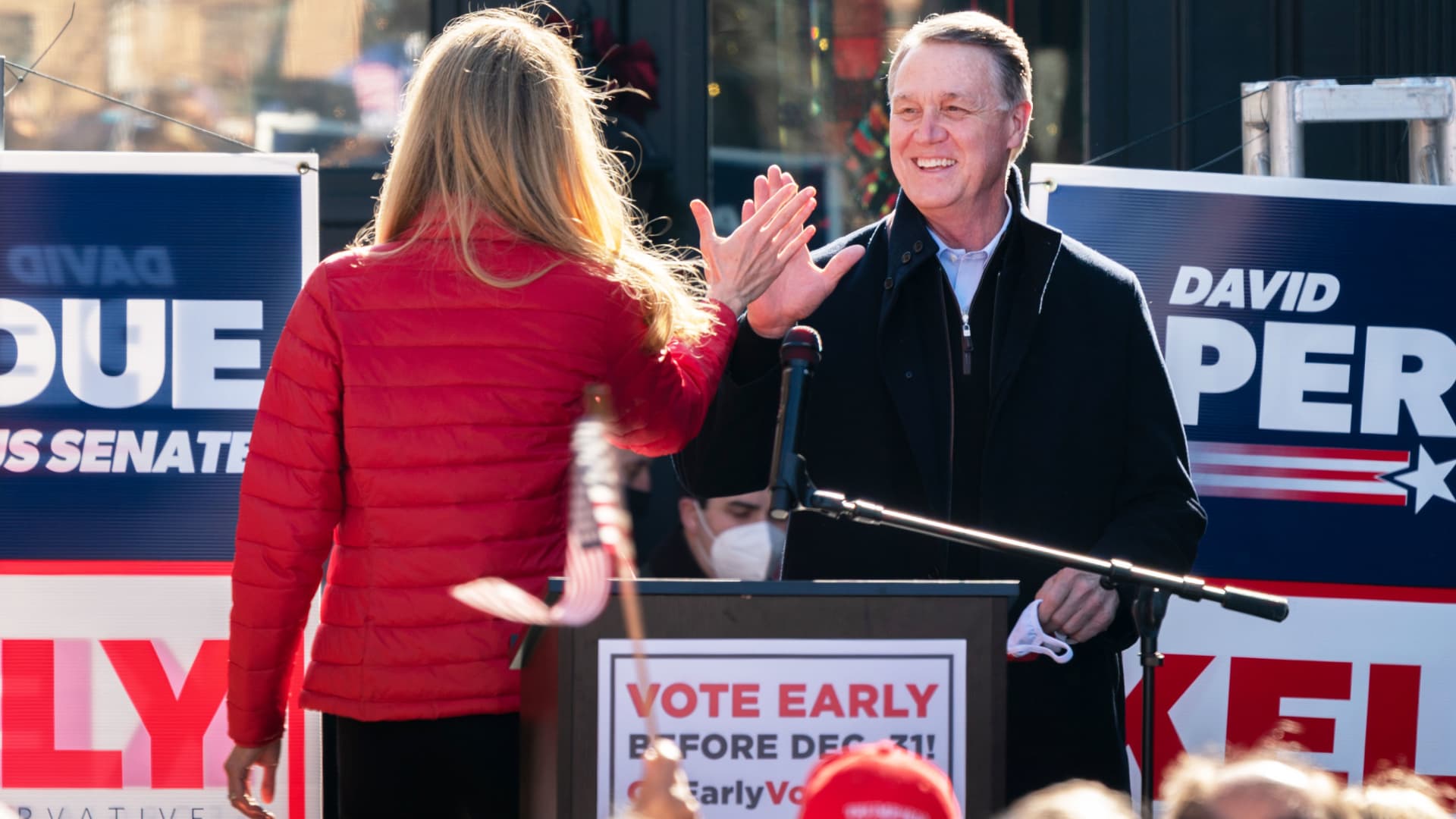 Senators Kelly Loeffler (R-GA) and David Perdue (R-GA) high five each other as Perdue takes the stage to speak during a campaign event on December 21, 2020 in Milton, Georgia.
