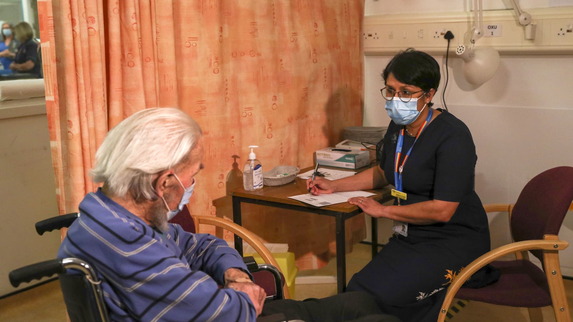Meghana Pandit, chief medical officer at the Oxford University NHS Trust, right, speaks to Trevor Cowlett, 88, ahead of him receiving the AstraZeneca Plc and the University of Oxford Covid-19 vaccine at the Churchill Hospital in Oxford, U.K., on Monday, Jan. 4, 2021. U.K. regulators cleared the shot last week, marking its first approval worldwide.