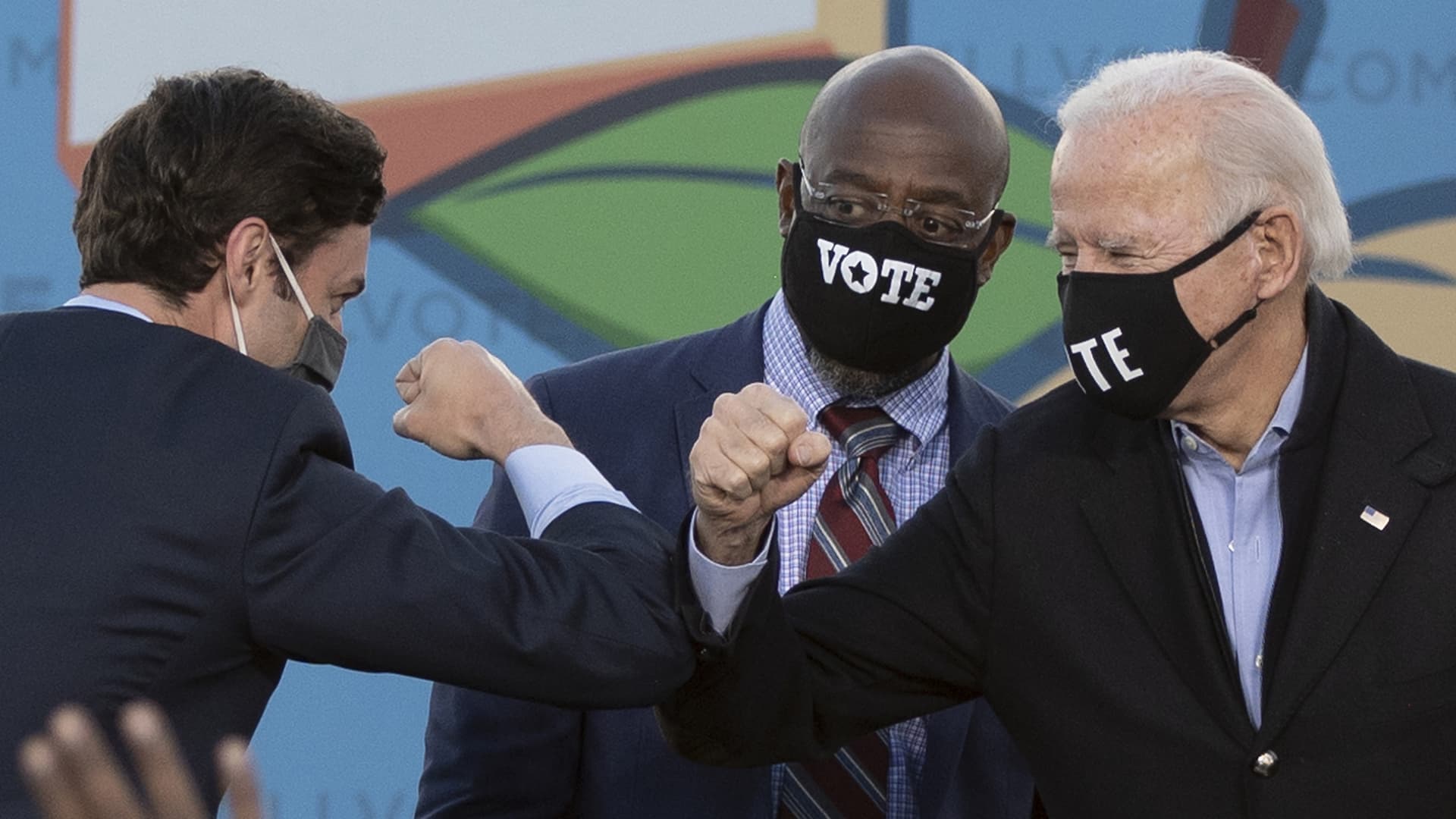 Democratic candidates for Senate Jon Ossoff (L), Raphael Warnock (C) and US President-elect Joe Biden (R) bump elbows on stage during a rally outside Center Parc Stadium in Atlanta, Georgia, on January 4, 2021.