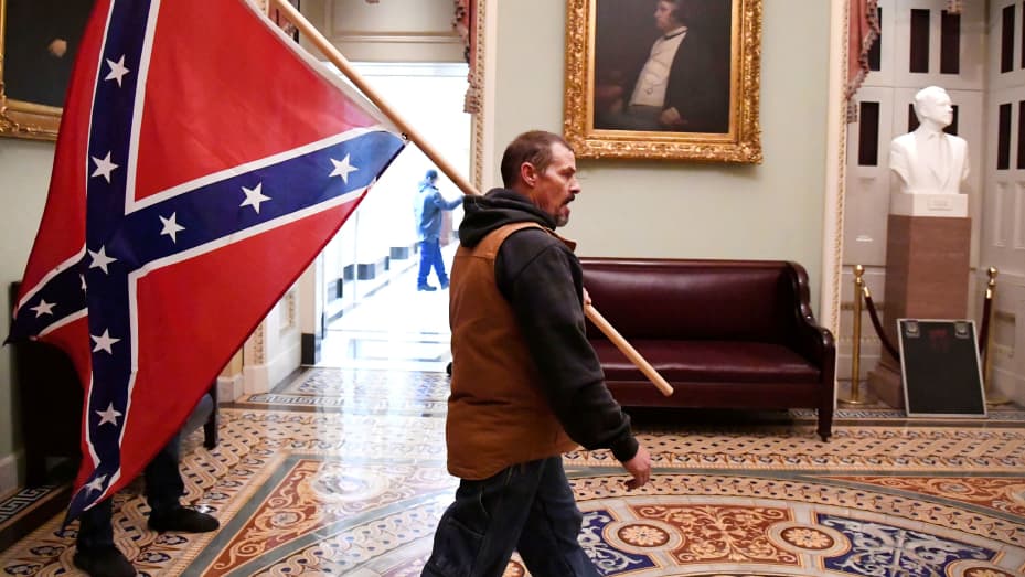 A supporter of President Donald Trump carries a Conferderate battle on the second floor of the U.S. Capitol near the entrance to the Senate after breaching security defenses, in Washington, January 6, 2021.