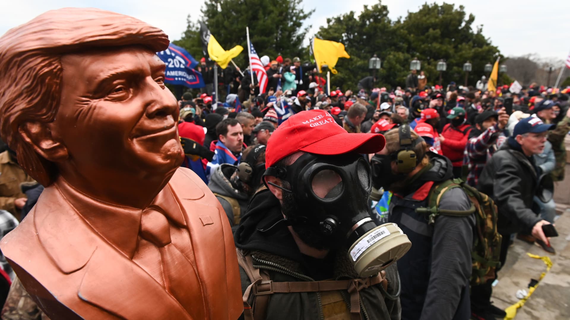 A supporter of US President Donald Trump wears a gas mask and holds a bust of him after he and hundreds of others stormed stormed the Capitol building on January 6, 2021 in Washington, DC.