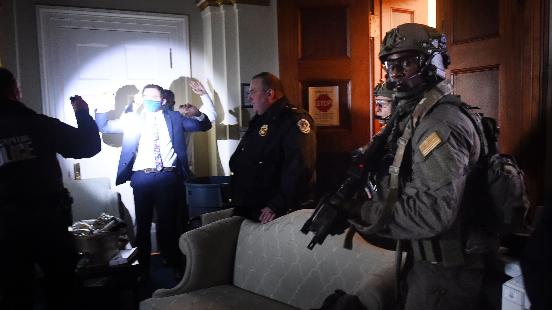 Congress staffers hold up their hands while Capitol Police Swat teams check everyone in the room as they secure the floor of Trump suporters in Washington, DC on January 6, 2021.
