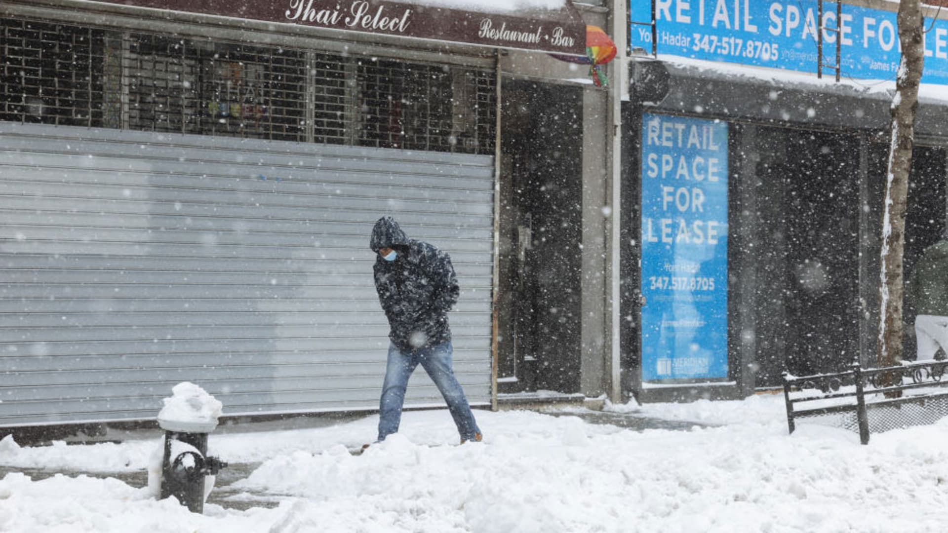 A pedestrian wearing a protective mask walks past a closed restaurant as snow falls in New York, on Thursday, Dec. 17, 2020.