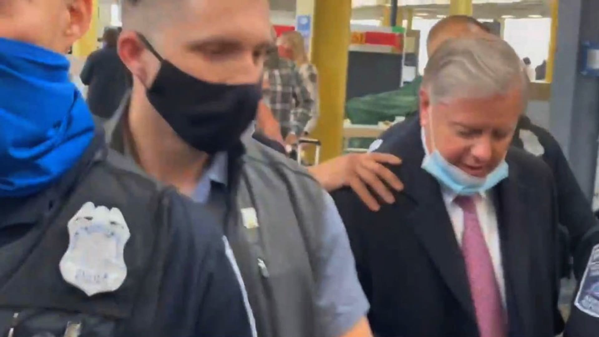 U.S. Senator Lindsey Graham is escorted by security personnel as Trump supporters berate him, at Reagan National Airport in Washington, U.S. January 8, 2021, in this still image obtained from a social media video. Courtesy of Oreo Express/Social