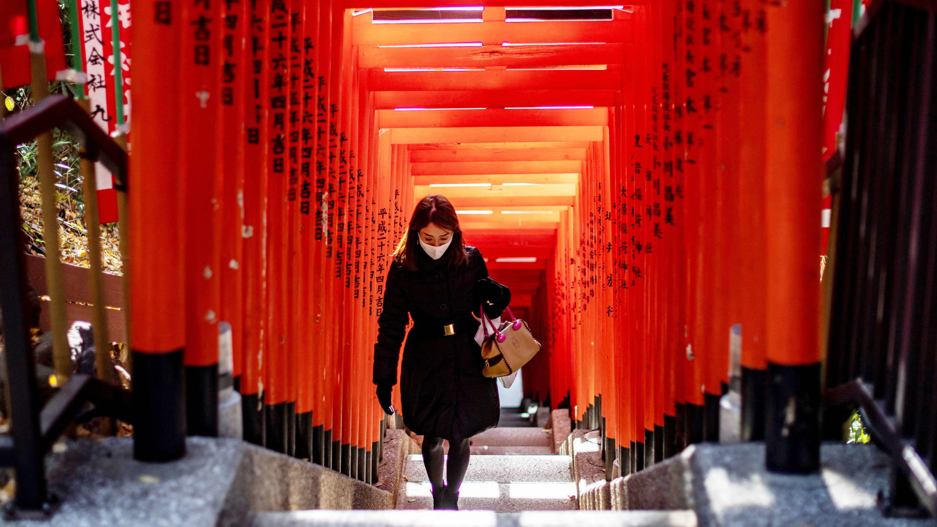 A woman wearing a face mask walks under a row of gates at Hie Shrine in Tokyo on January 7, 2021.