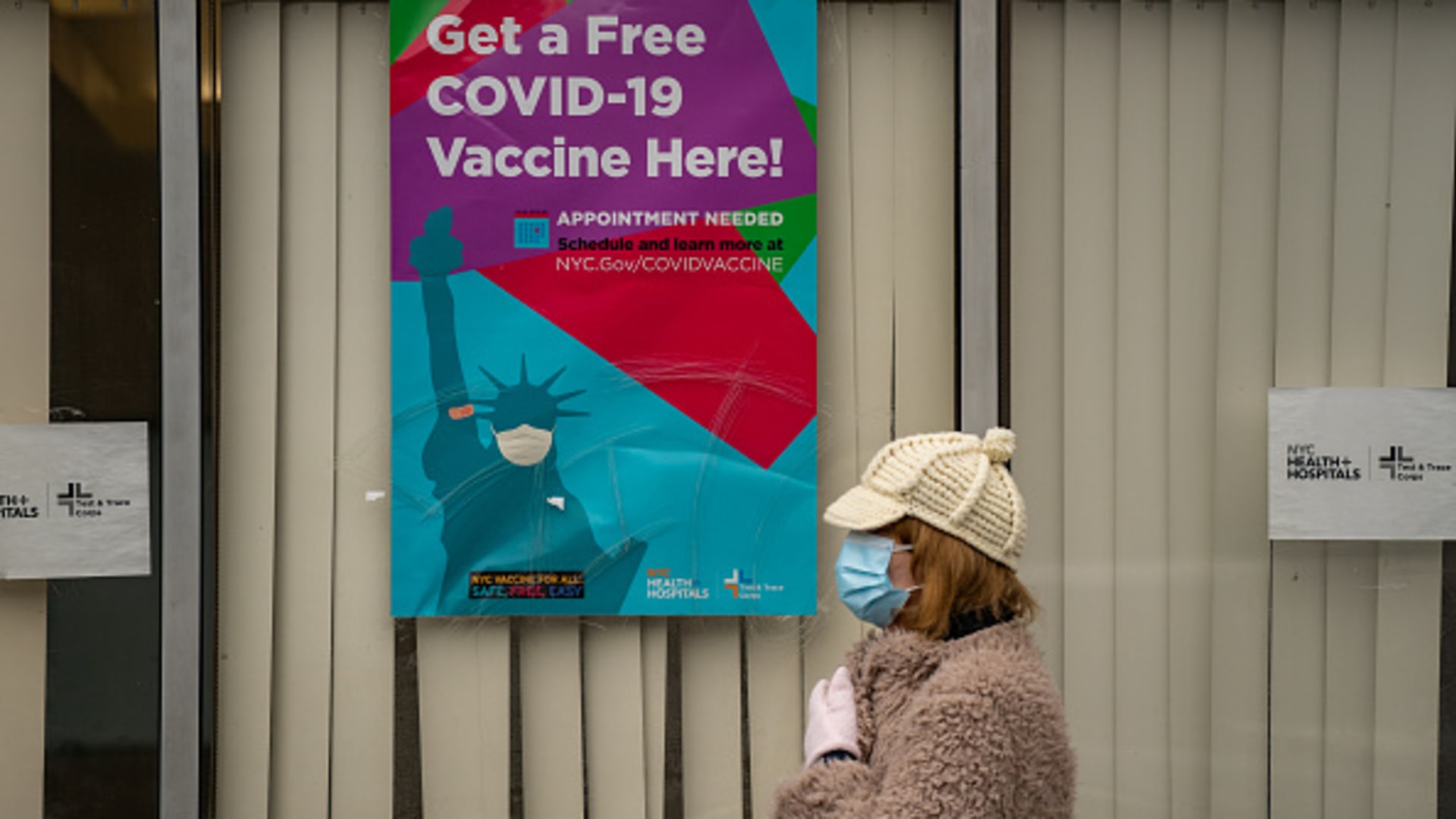 A person wearing a protective mask stands outside a Covid-19 vaccination site at Bathgate Industrial Park in the Bronx borough of New York, U.S., on Monday, Jan. 11, 2021.