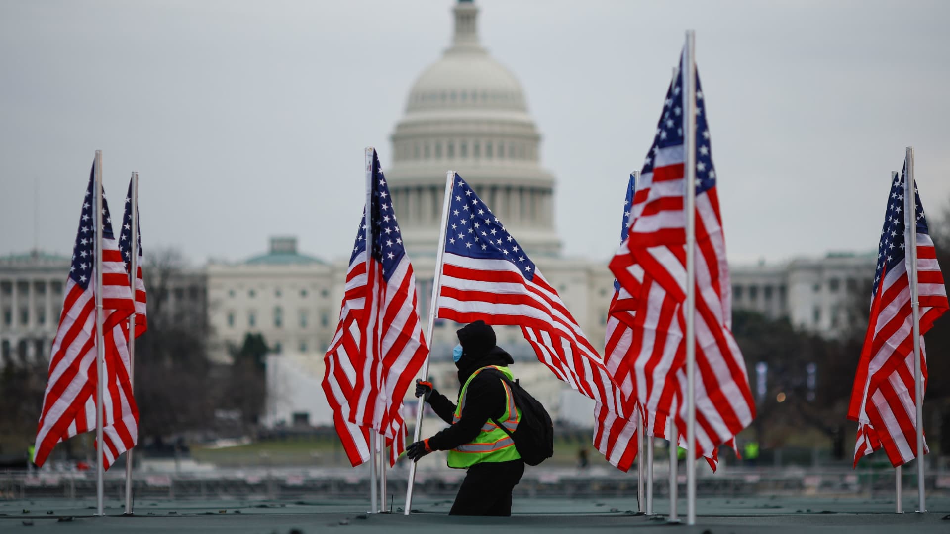 A worker installs U.S. flags as part of a Covid-19 memorial on the National Mall in Washington, D.C., on Jan.18, 2021.
